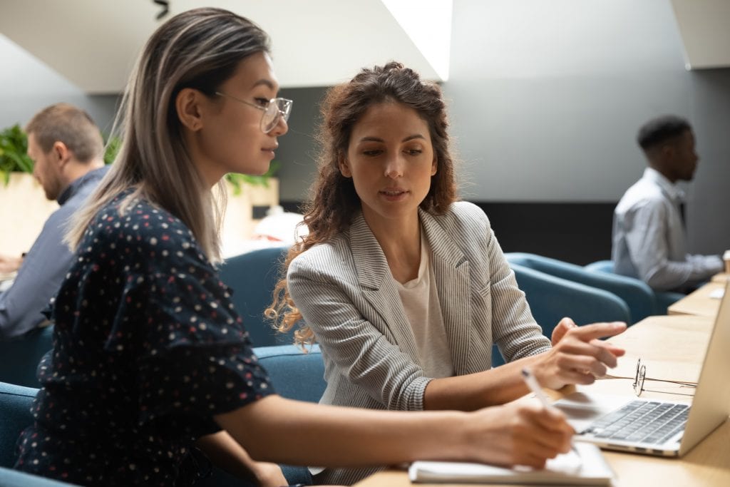 two women sitting in front of a laptop in discussion