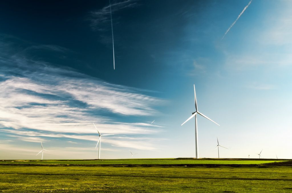 Several windmills in green field with blue skies